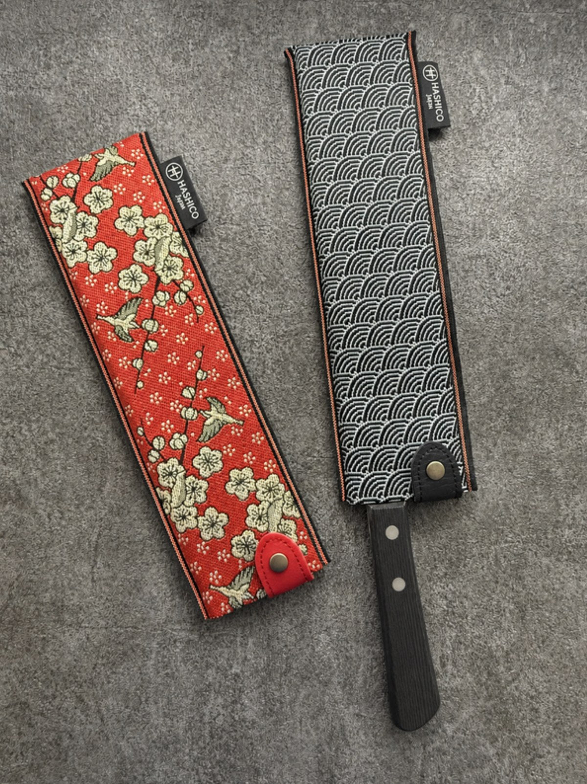 Two SAYACA saya (knife cases), in the Kacho and Seigaiha patterns, on a stone surface
